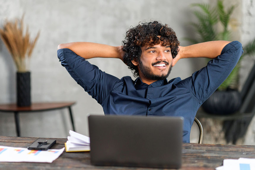 Smiling foreign professional at a desk and is dreaming of his future job in Germany